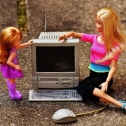 To barbie-dukker sidder foran en computer