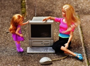 To barbie-dukker sidder foran en computer